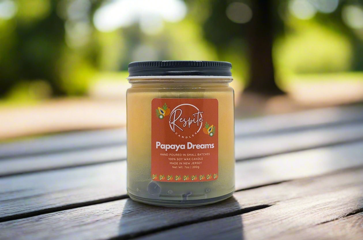 Candle jar labeled 'Papaya Dreams' with a visible brand logo on a white background