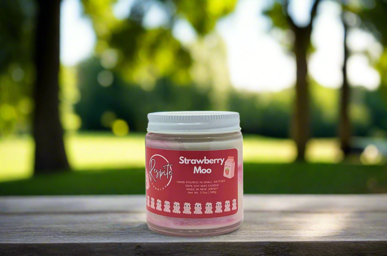 Jar of Strawberry Moo candle with a red label on a white background