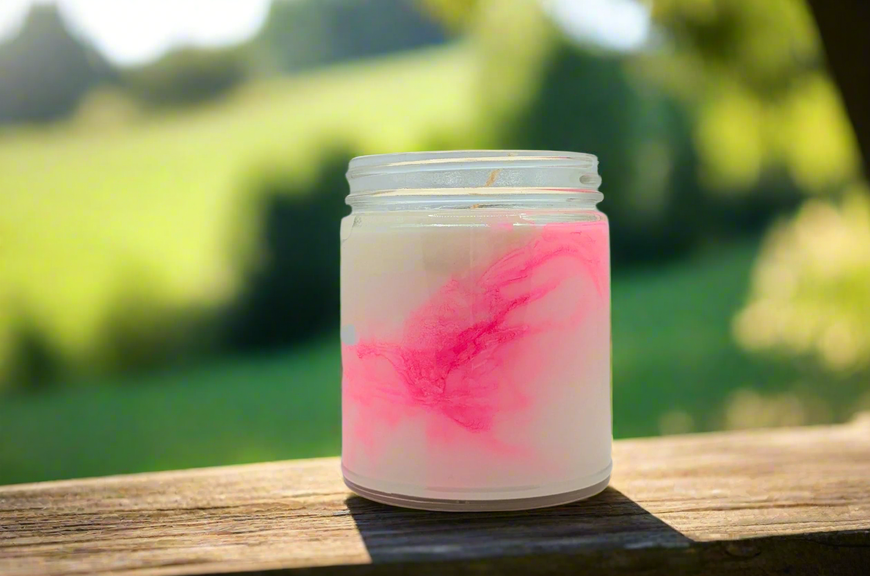 Candle in a glass jar with pink and white design on a light gray background