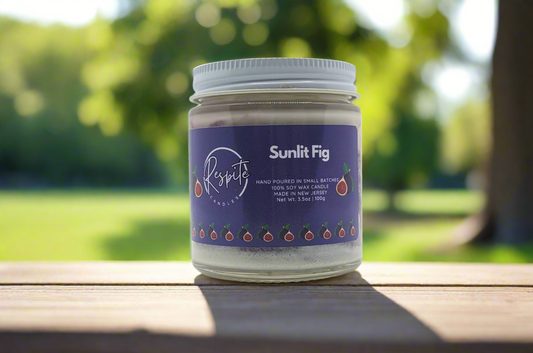 Jar of 'Sunlit Fig' candle with a purple label on a white background