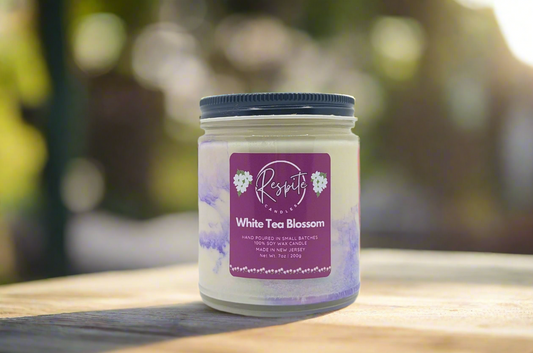 Candle jar labeled 'White Tea Blossom' with a purple label on a white background